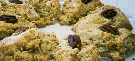 A plate of freshly baked scones topped with pecans.