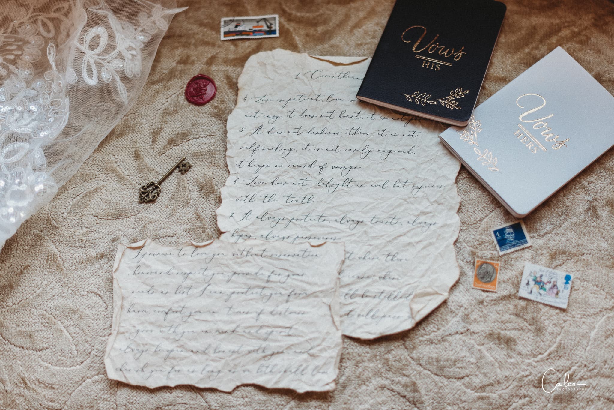 A collection of vintage letters, wedding vows notebooks, a key, and postage stamps arranged on a textured fabric background.
