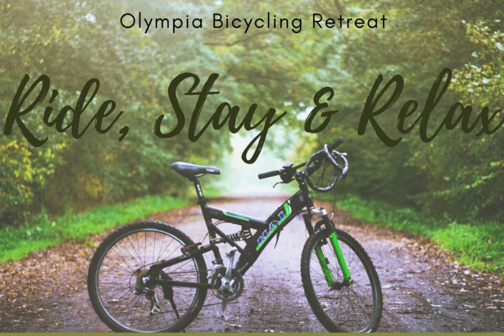 A bicycle on a path surrounded by trees, promoting the Olympia Bicycling Retreat with the phrase "Ride, Stay & Relax."