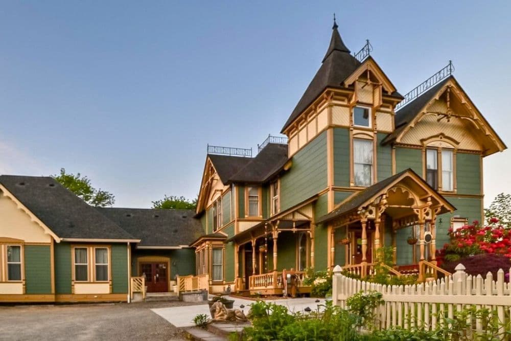 An exterior view of a colorful Victorian-style house with multiple gables and ornate details.