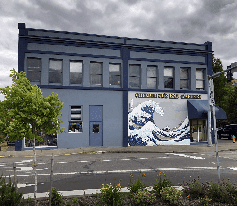 A blue building featuring the sign "Childhood's End Gallery" and a large wave mural on its exterior.