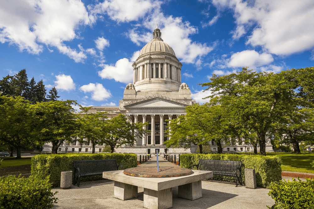 The Washington State Capitol building surrounded by trees under a blue sky.