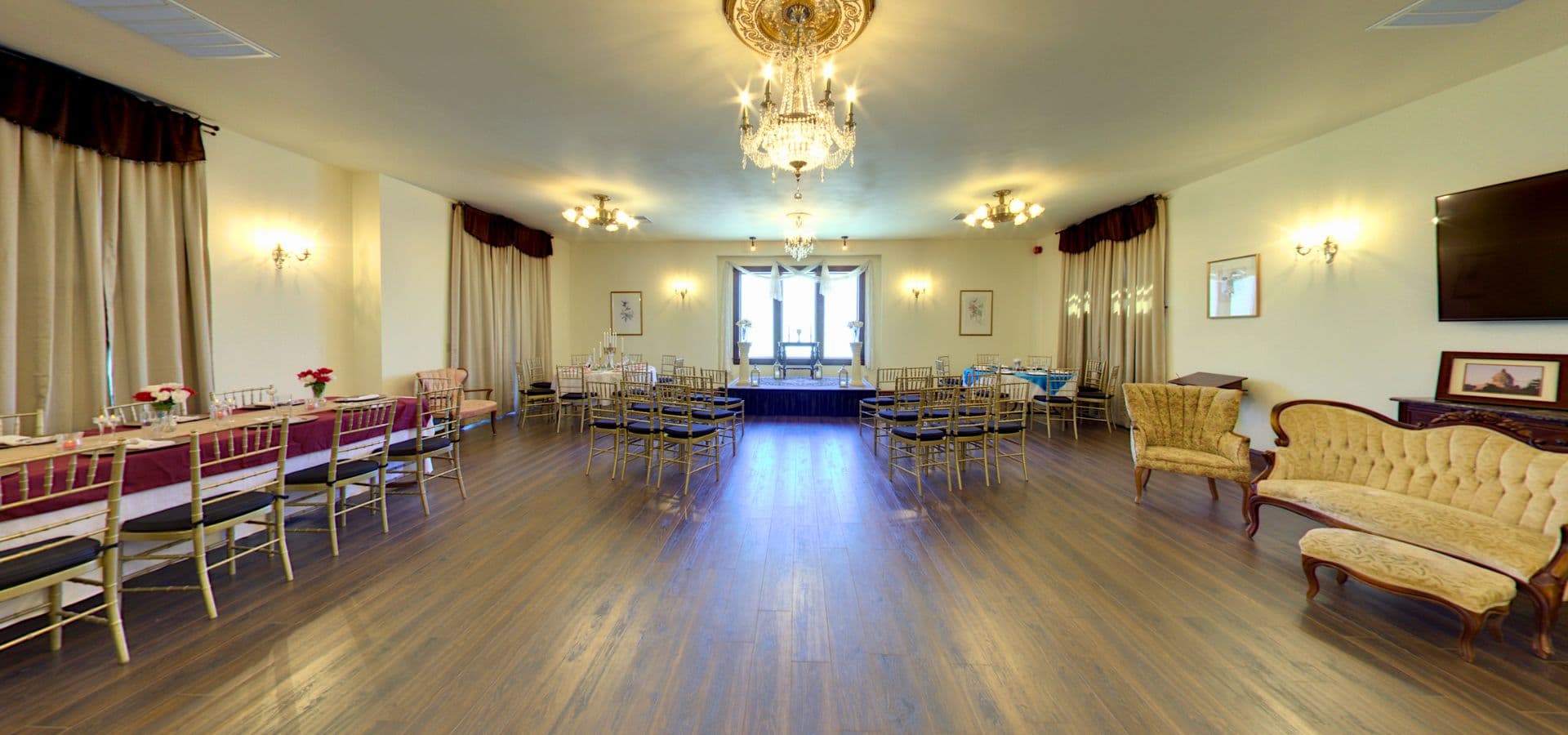 A spacious, elegantly decorated event room with tables, chairs, and large windows.