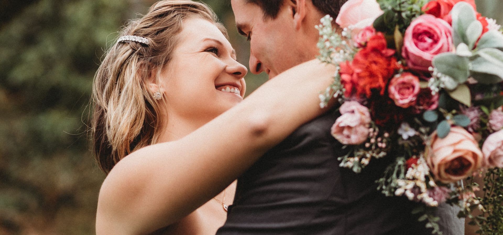 A couple shares a joyful embrace, gazing into each other's eyes while surrounded by vibrant flowers.