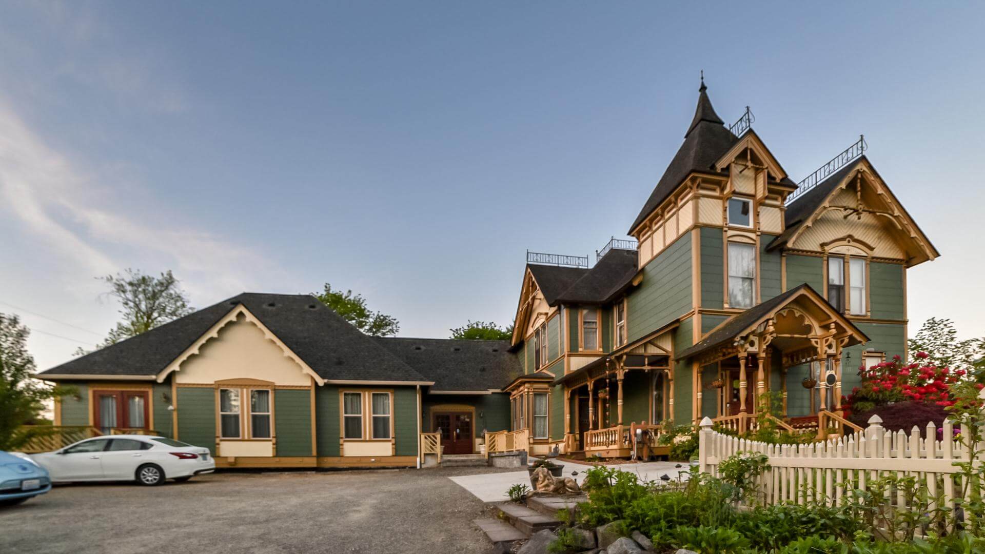 A picturesque Victorian house with ornate details and a surrounding garden.
